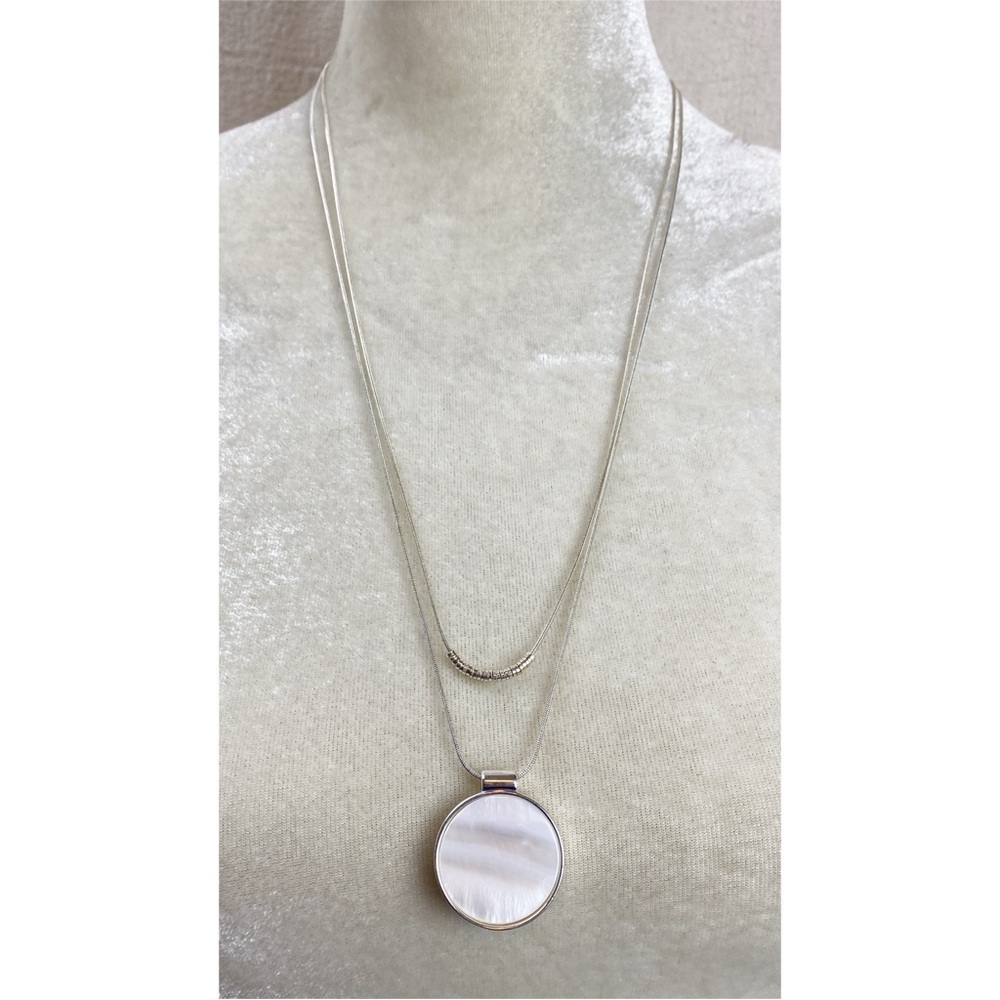 Long silver tone multi-strand necklace with a round mother-of-pearl pendant